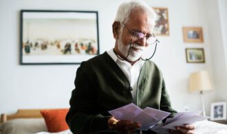 an elderly man with glasses smiles as he checks the mail in Assisted Living, Oceanside CA